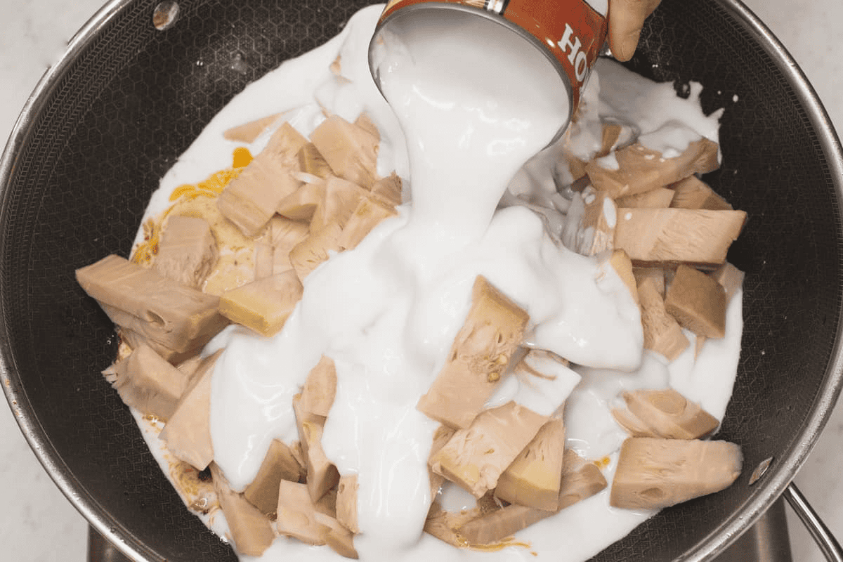 Adding coconut milk to the langka and other ingredients in the wok.