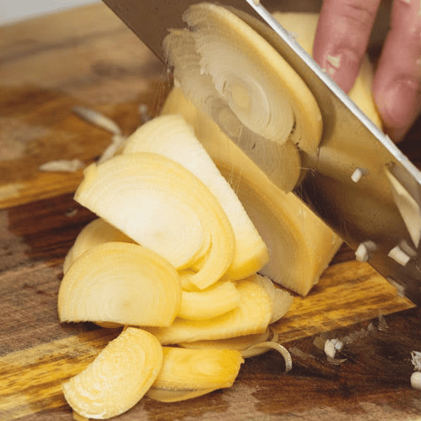 Slicing banana blossoms on a cutting board.