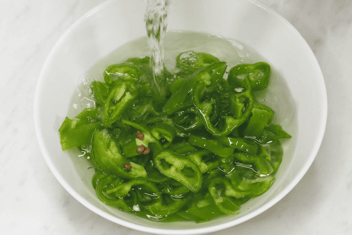 Blanching the sliced chili peppers in a bowl.