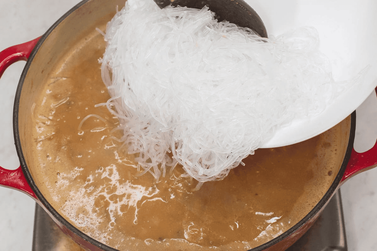 Adding the softened sotanghon into the mixture.