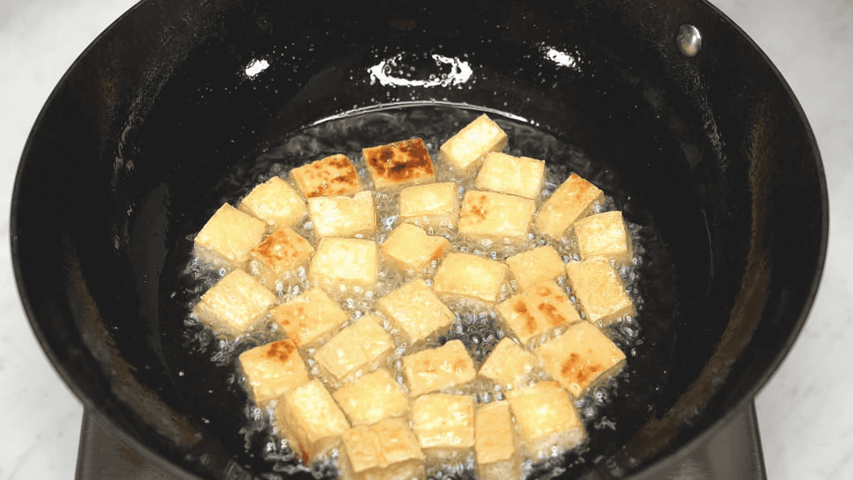 Frying the tofu cubes in a wok.
