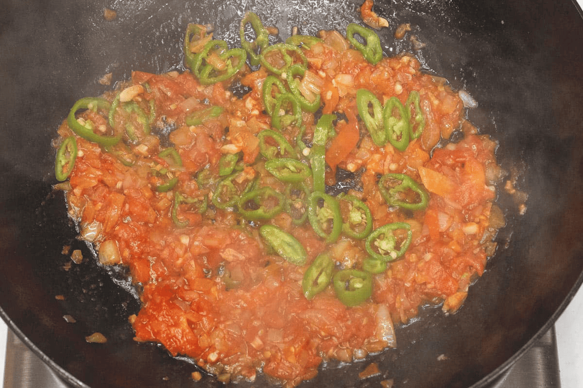 Adding the chilies to the other aromatics in the wok.