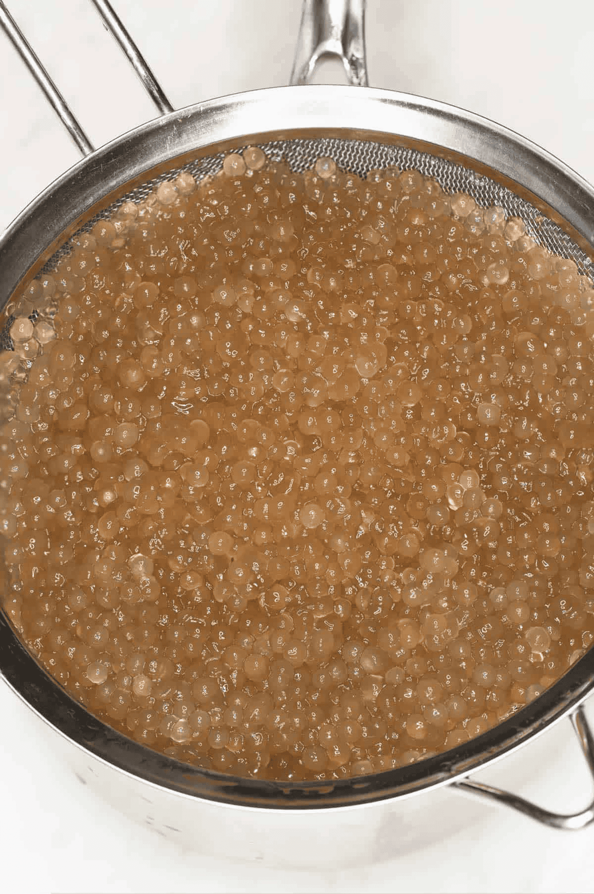 Draining cooked sago in a fine-mesh strainer.