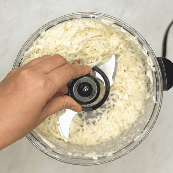 Fitting a blade in the food processor with shredded cassava.