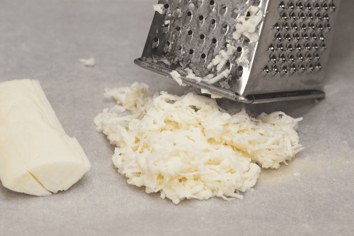 Grated cassava on a parchment paper -lined cutting board.
