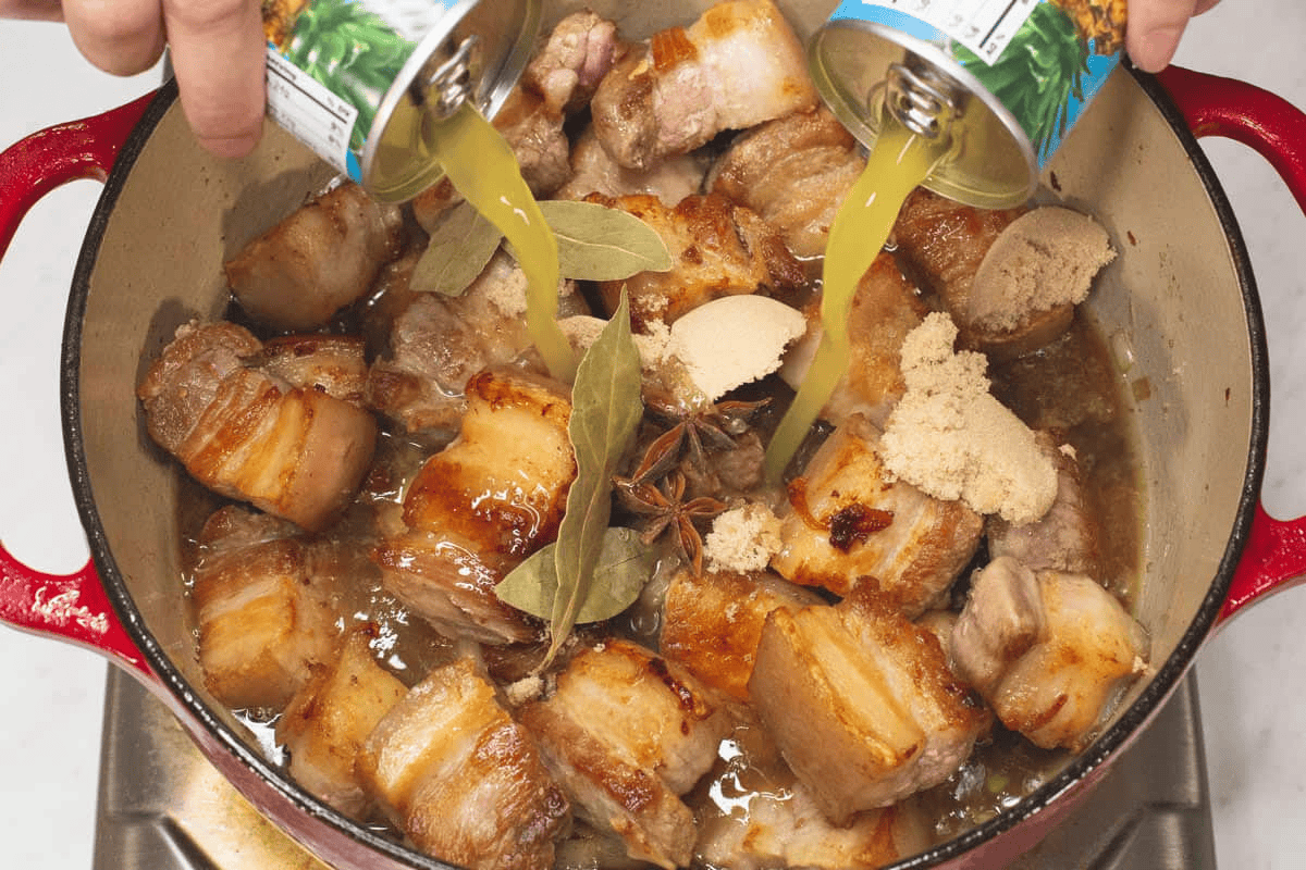 Adding pineapple juice to the meat and other ingredients in the pot.