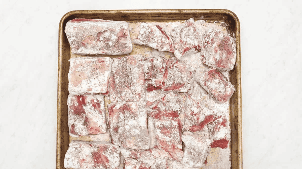 Beef short ribs and chuck are coated in flour.