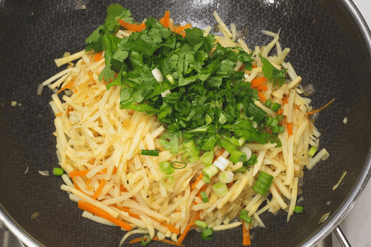 Added the scallions and cilantro to the bamboo shoots and carrots in the wok.