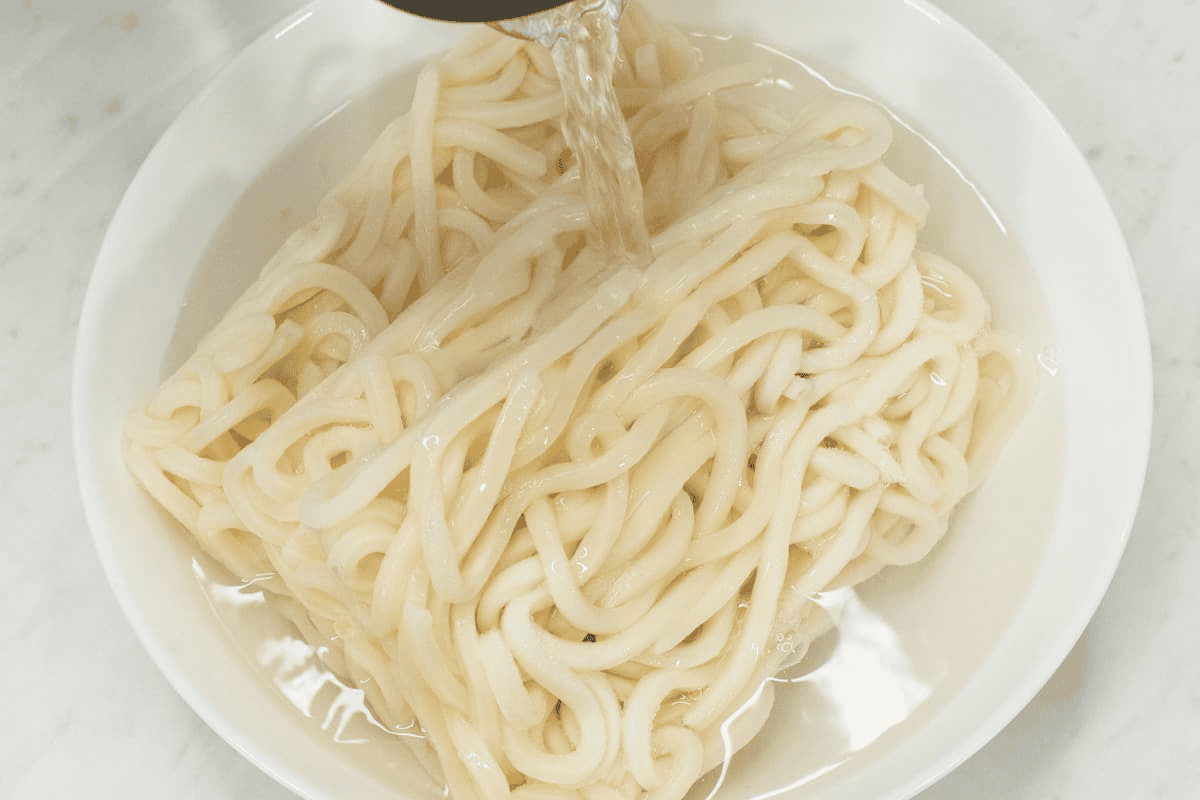 Soaking udon noodles with water in a bowl.