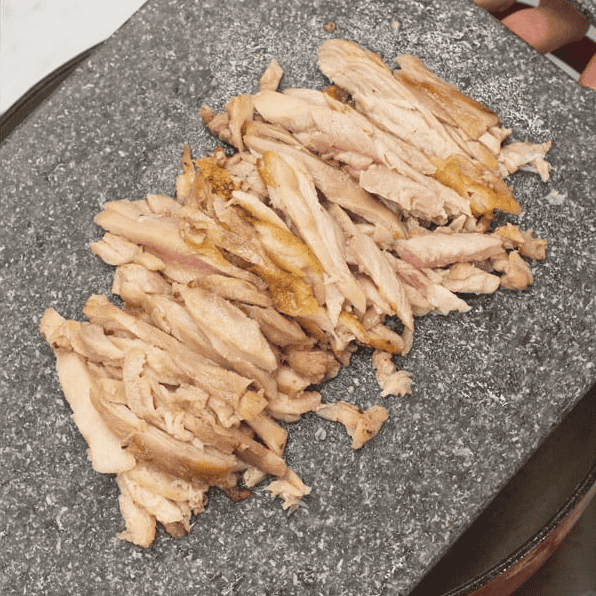 Shredded cooked chicken on a cutting board.