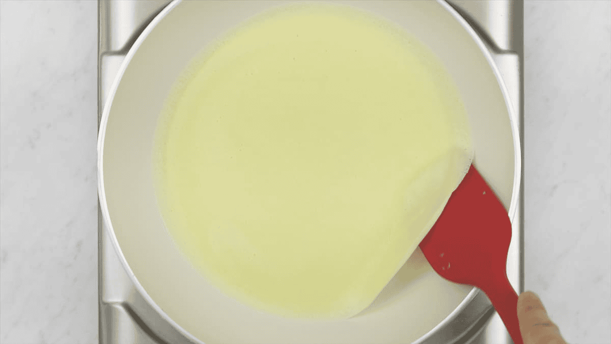 Lifting the crepe from the pan using a spatula.