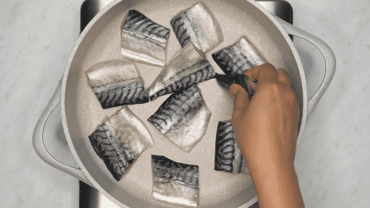 Arranging cuts of fish fillet on the bottom of the pan.