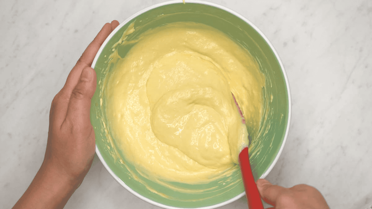 Mixing the cheesecake batter in the bowl using a spatula.