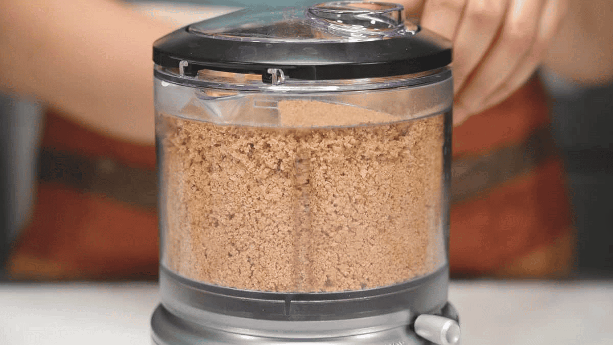Combining graham crackers and other ingredients in a food processor.