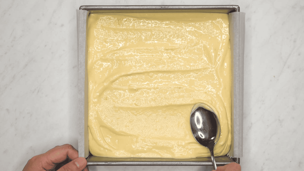 Spreading the cheesecake batter using a spoon.