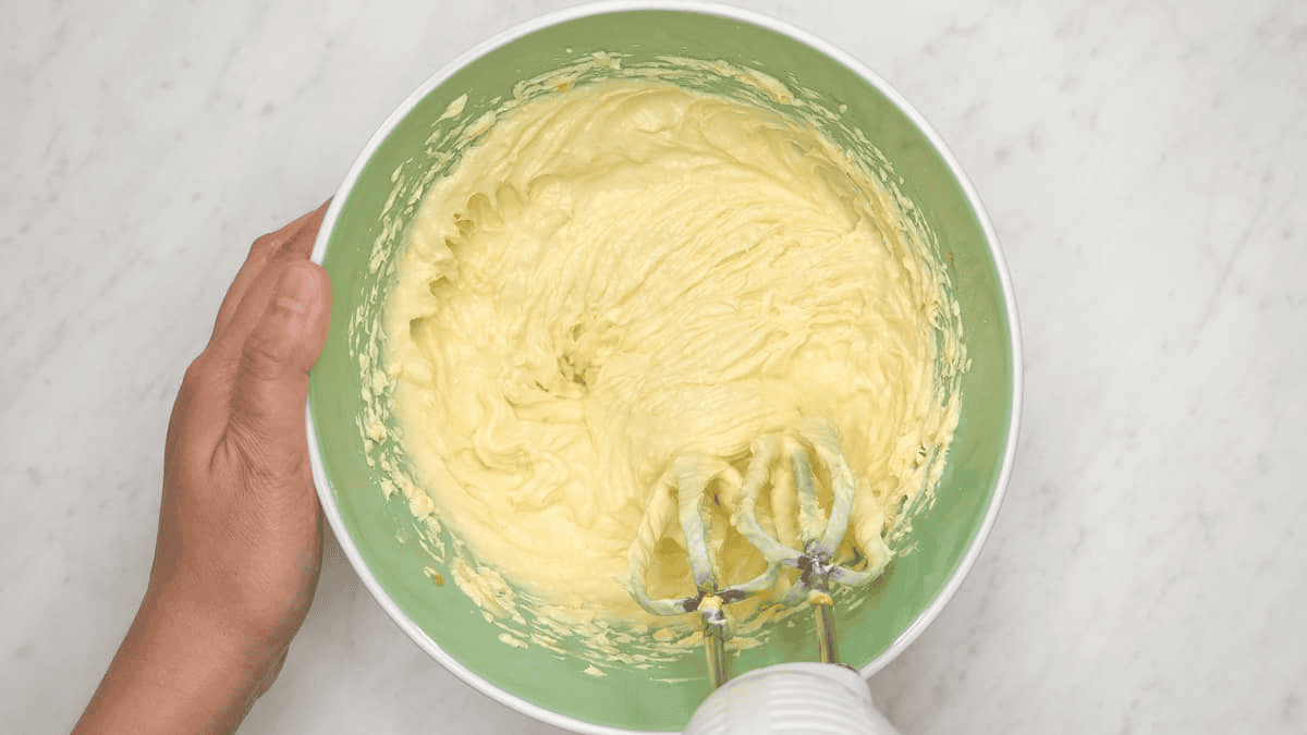 Mixing the cheesecake batter ingredients using a hand-held mixer.