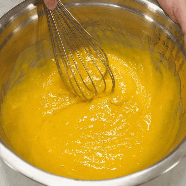Whisking the mango cake wet ingredients until smooth.