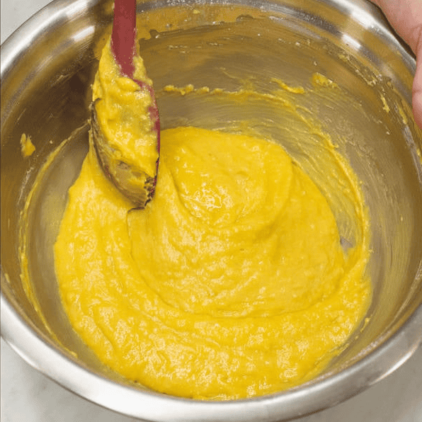 Mixing the dry ingredients into the yellow mango batter.