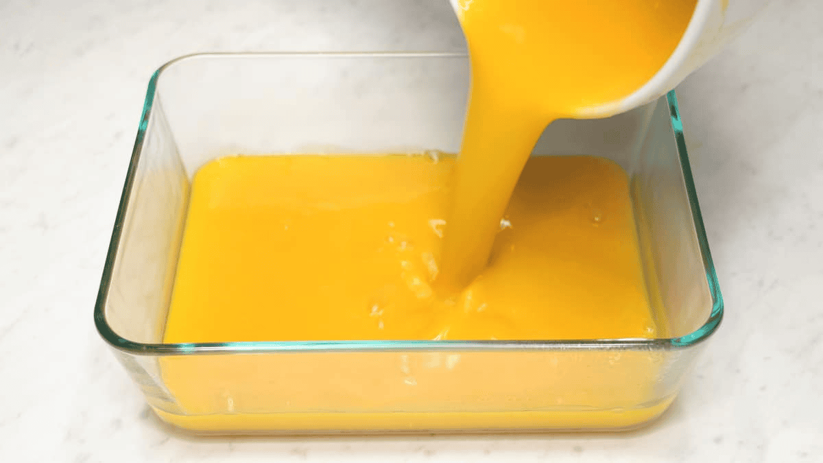 Pouring the mango gelatin mixture into the pan.