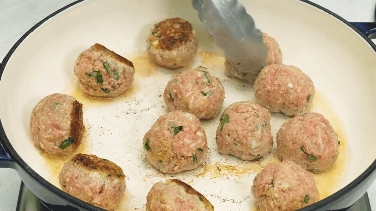 Searing the meatballs in a saute pan.