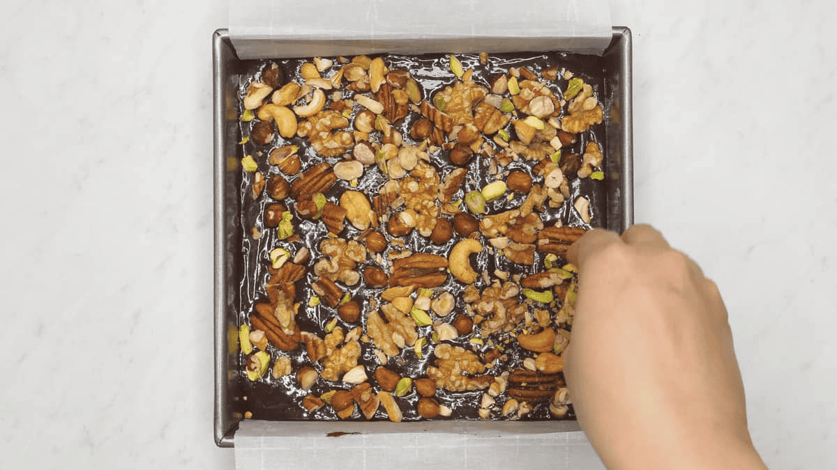 Adding nuts to the brownie batter in the pan.