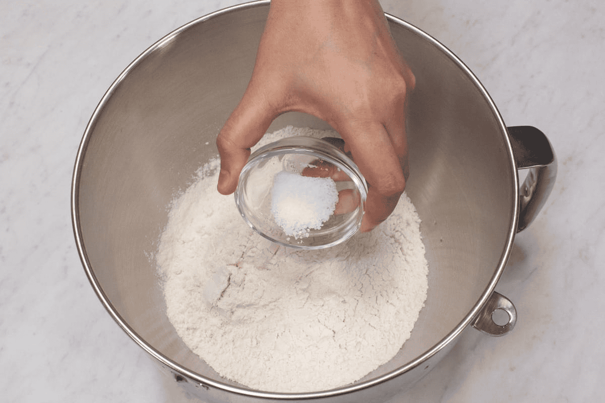 Adding the salt to the flour in the bowl.