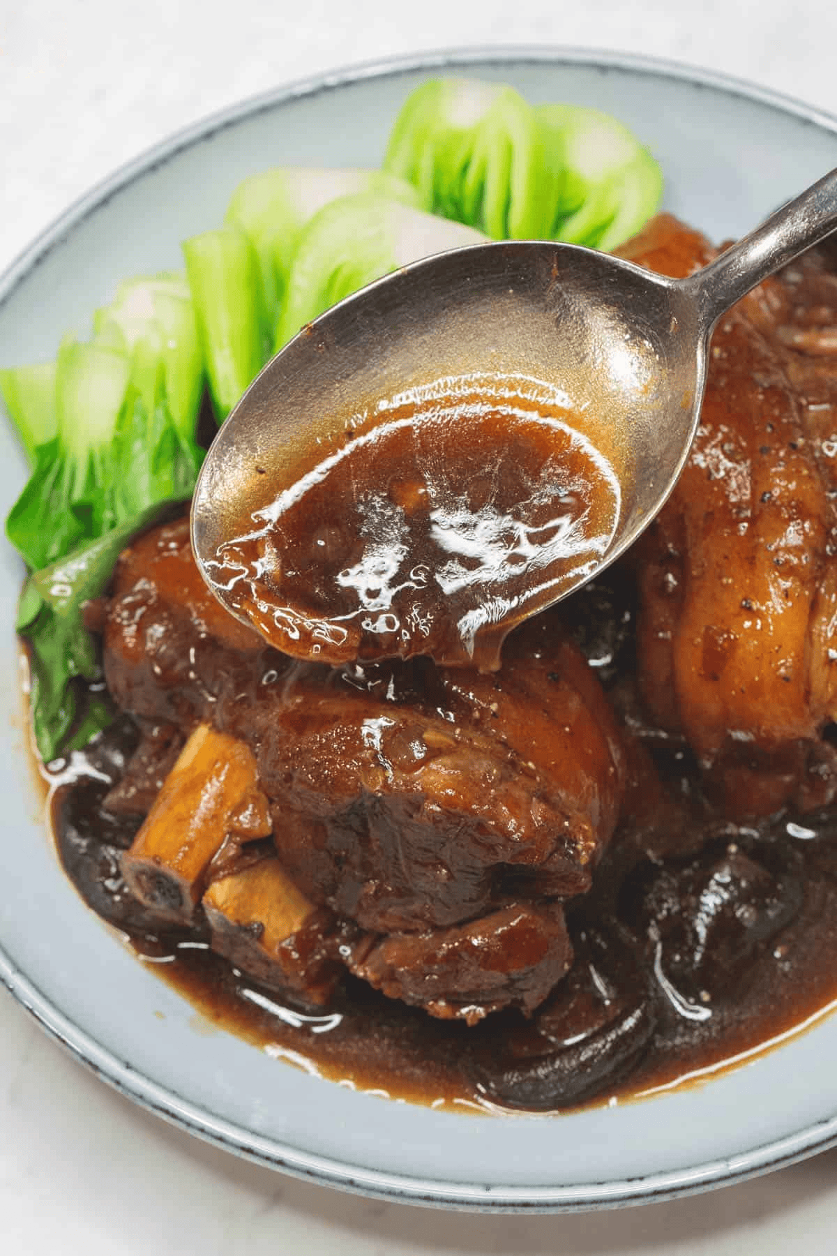 Pouring the sauce over the Pata Tim on the plate.