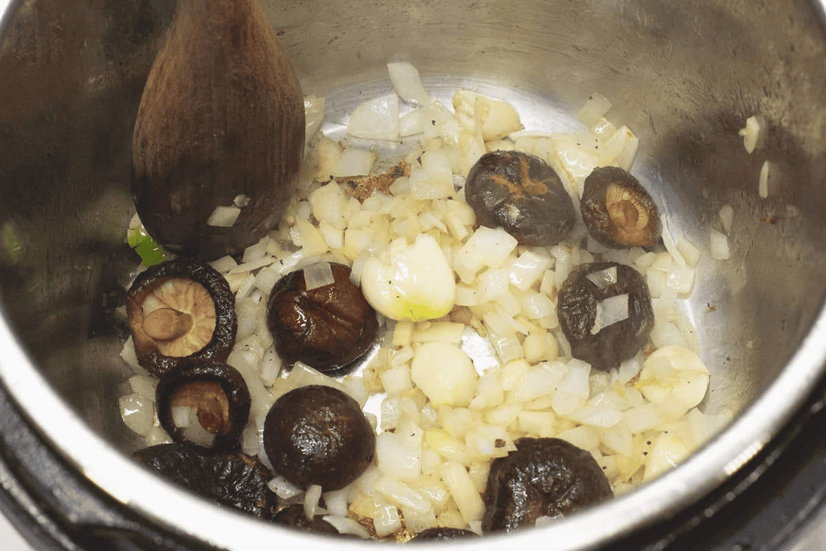 Sauteing the aromatics with the shiitake mushrooms in the pot.