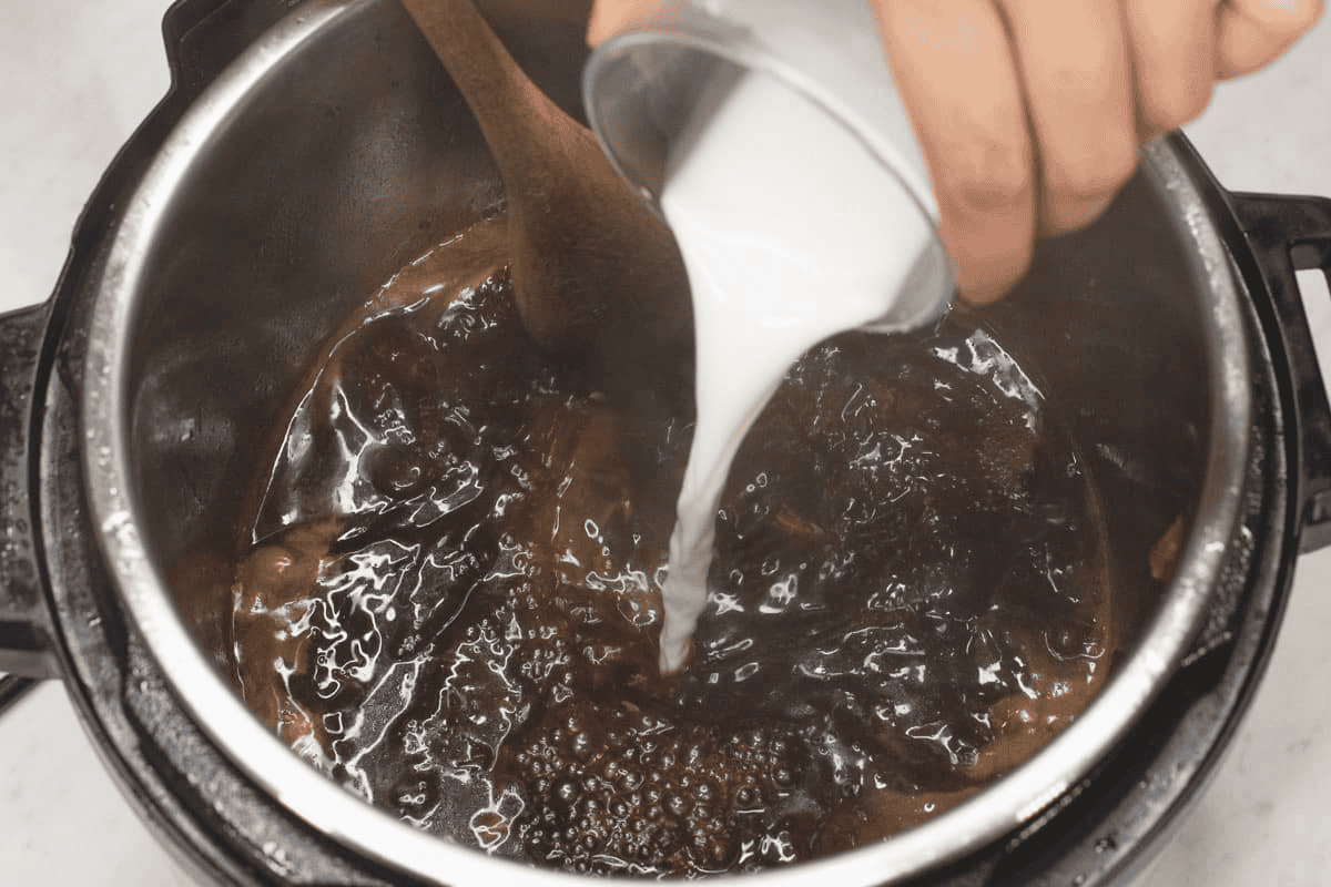 Pouring the cornstarch slurry to the sauce in the pot.