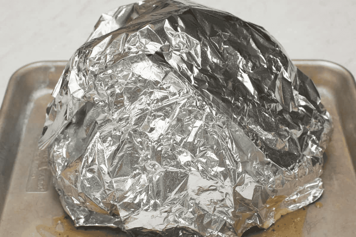 Covering the ham with foil.