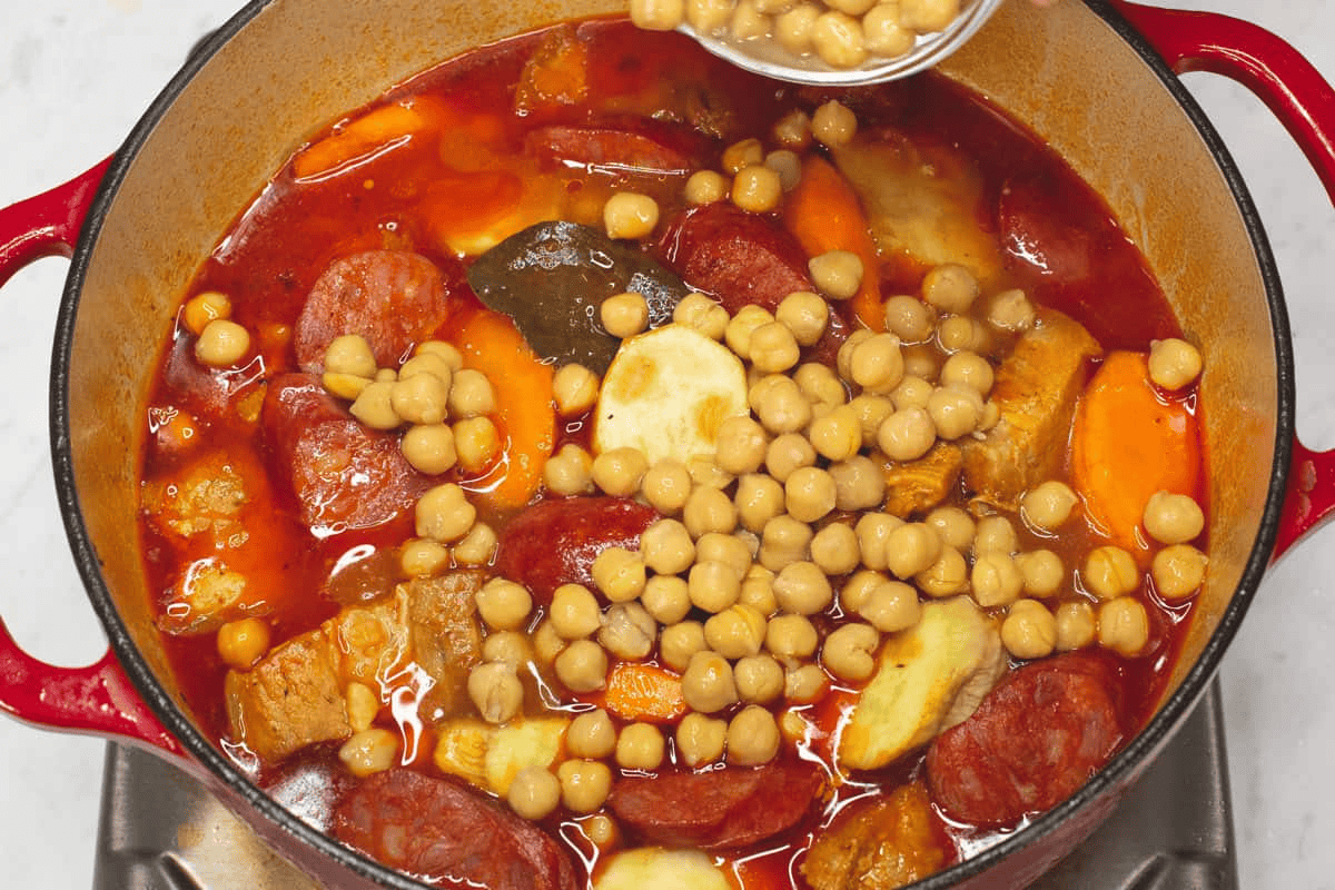 Adding the chickpeas to the meat and other ingredients in the pot.