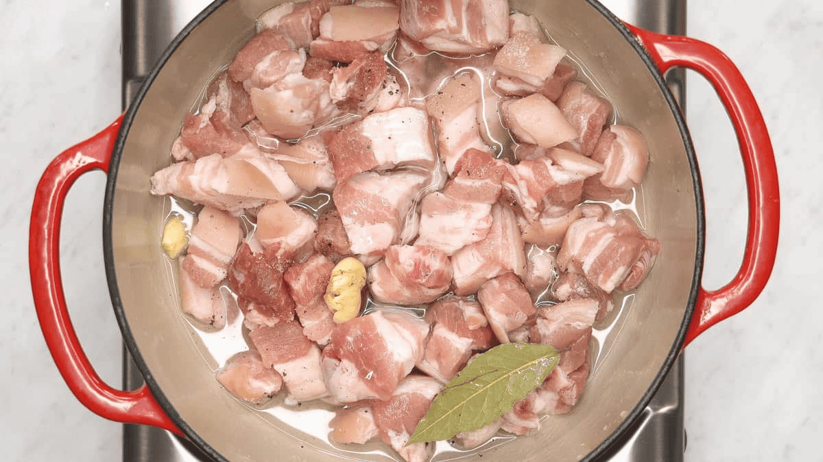 Pork and aromatics partially submerged in water
