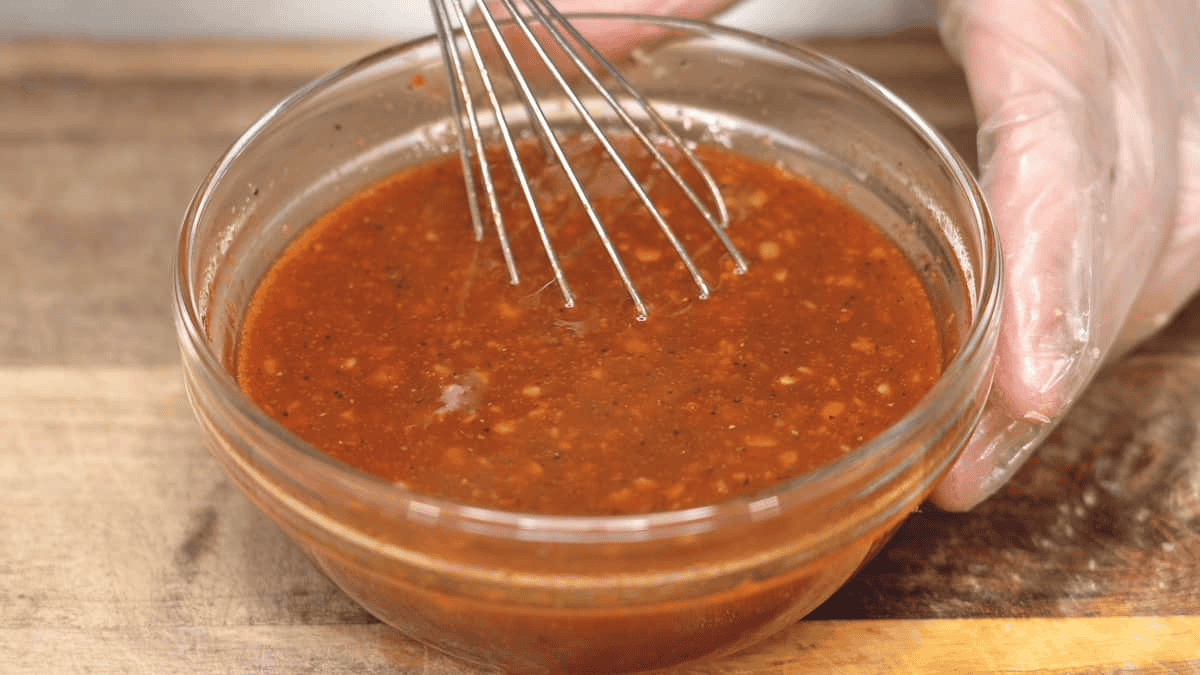 Mixing the tocino marinade in a bowl with a whisk.