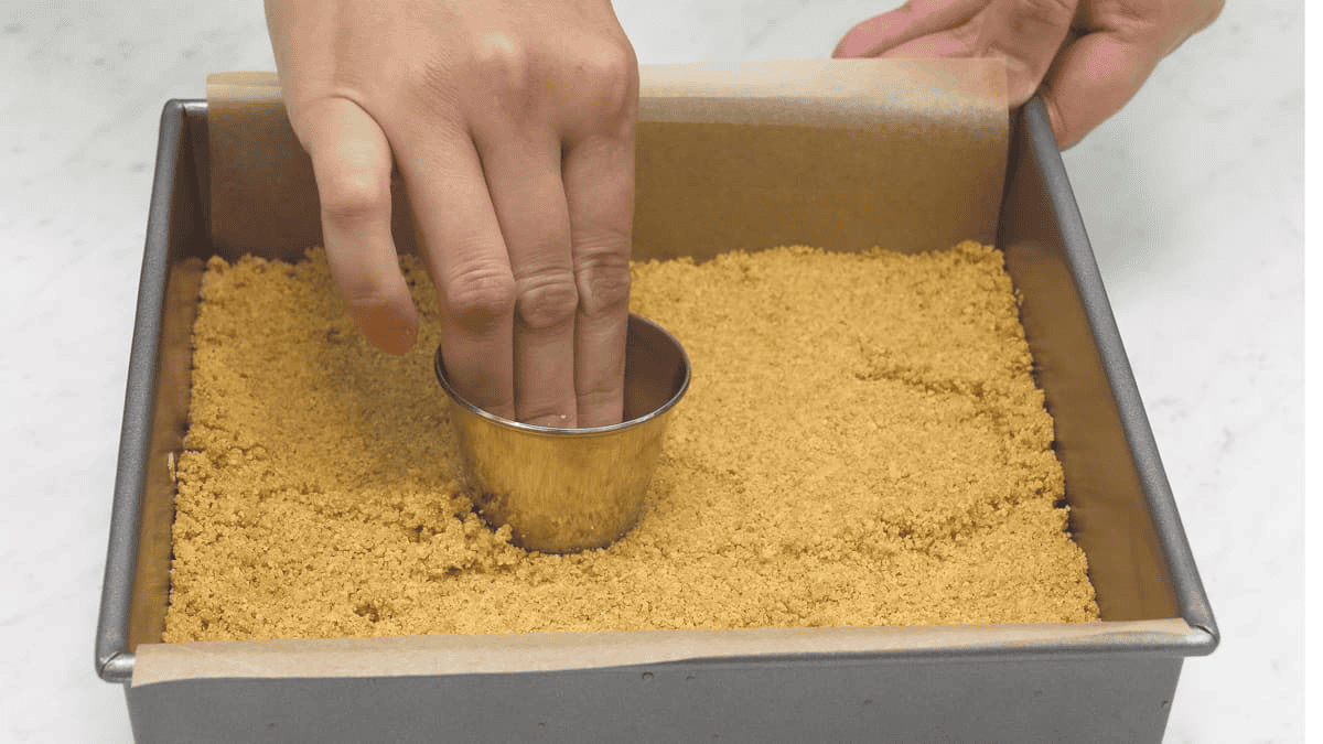 Pressing the crust firmly into the bottom of the pan with a ramekin.