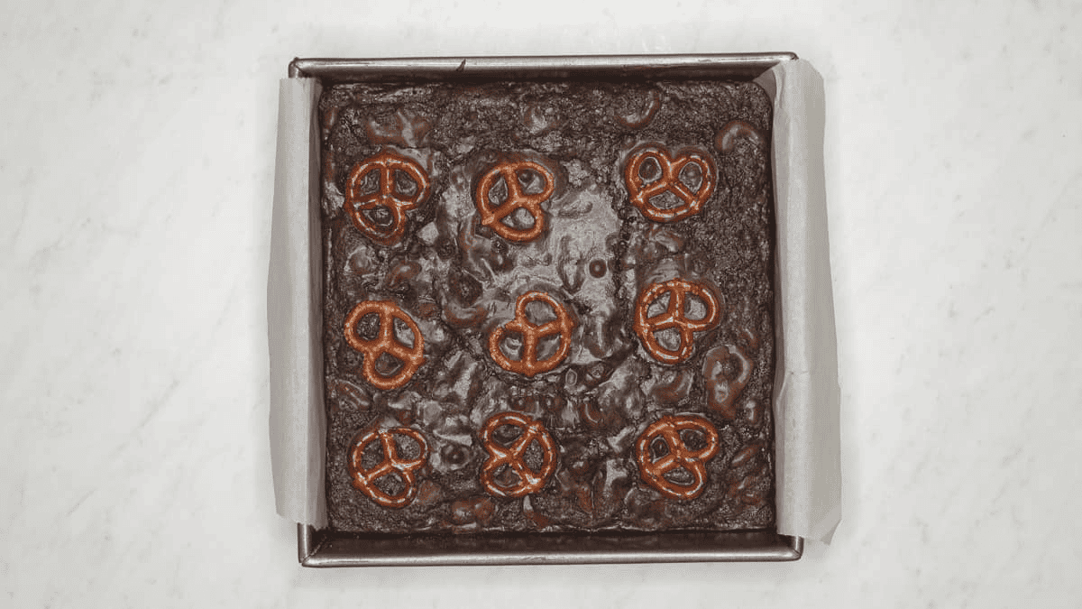 Baked brownies with pretzels on top.