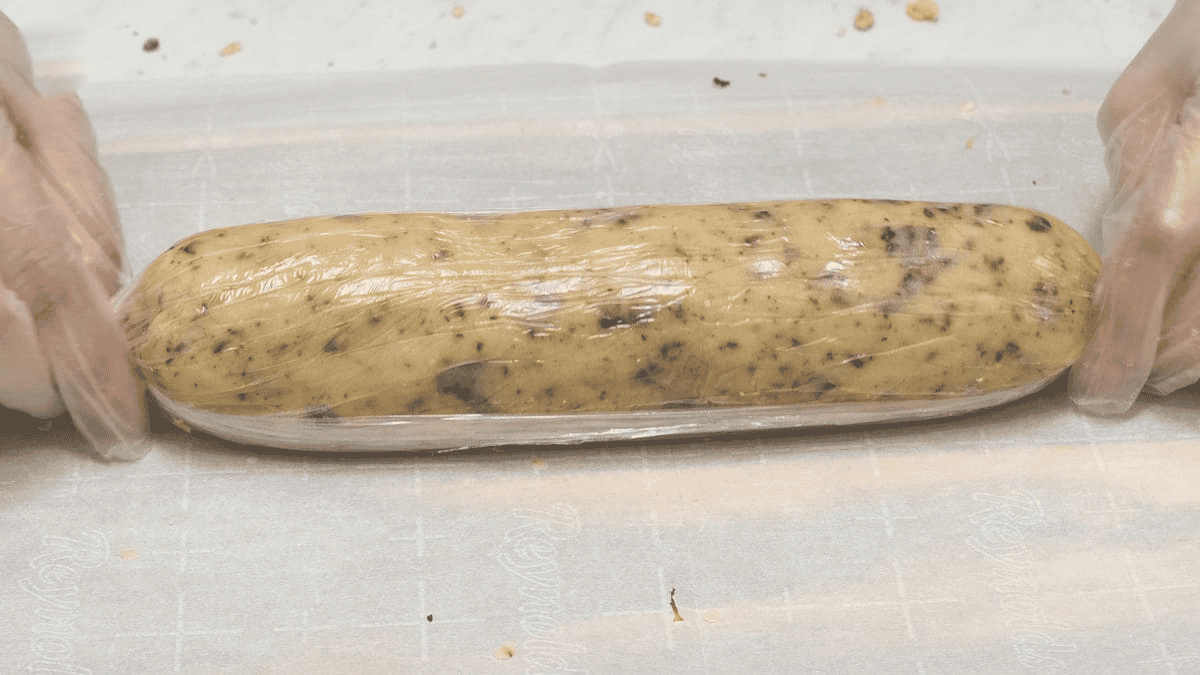 Rolling the cookie dough log wrapped in plastic wrap.