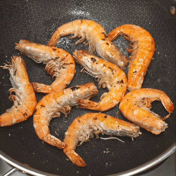 Searing shrimp in a skillet.