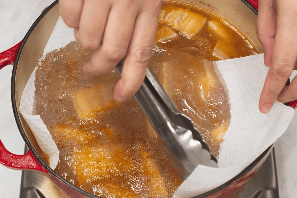 Laying a piece of paper towel on top of the broth to absorb excess oil.