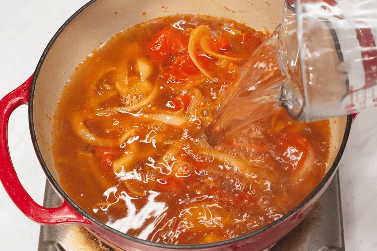 Adding the water to the aromatics in the pot.