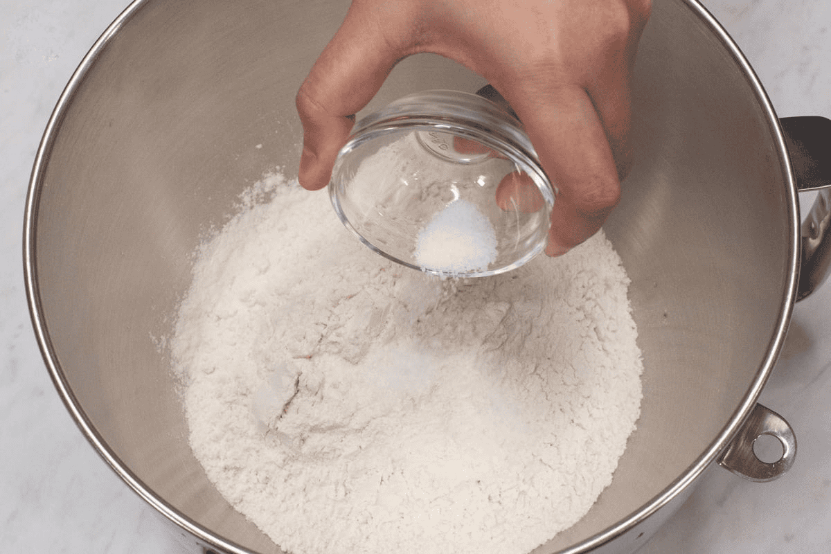 Adding salt to the flour in the bowl.