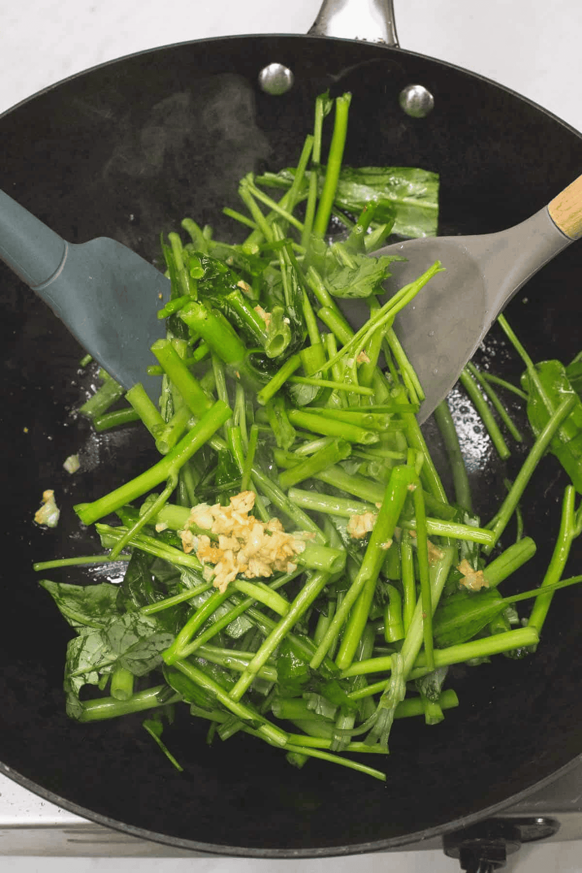Tossing the kangkong stems in the wok.