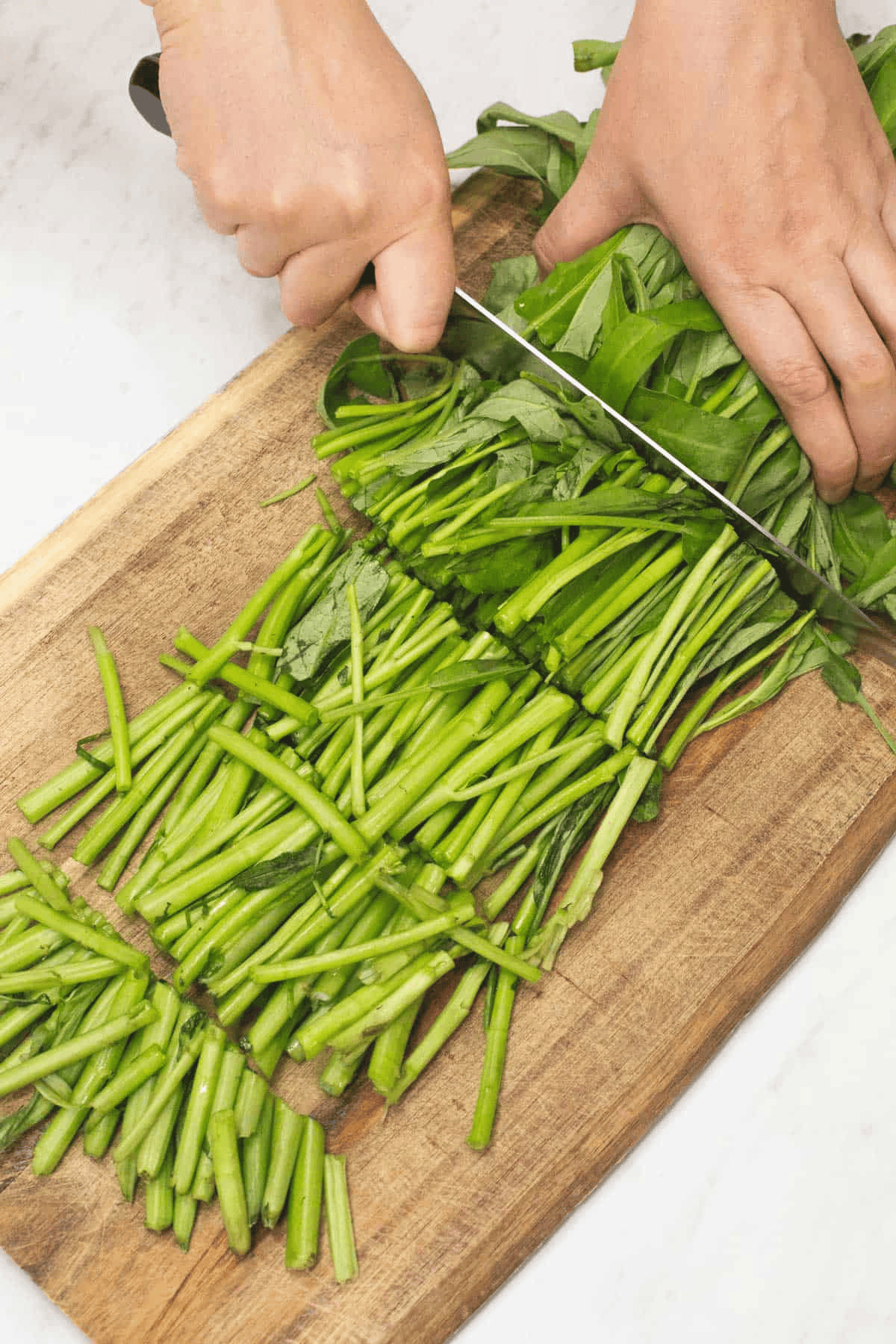 Cutting the kangkong into sections.