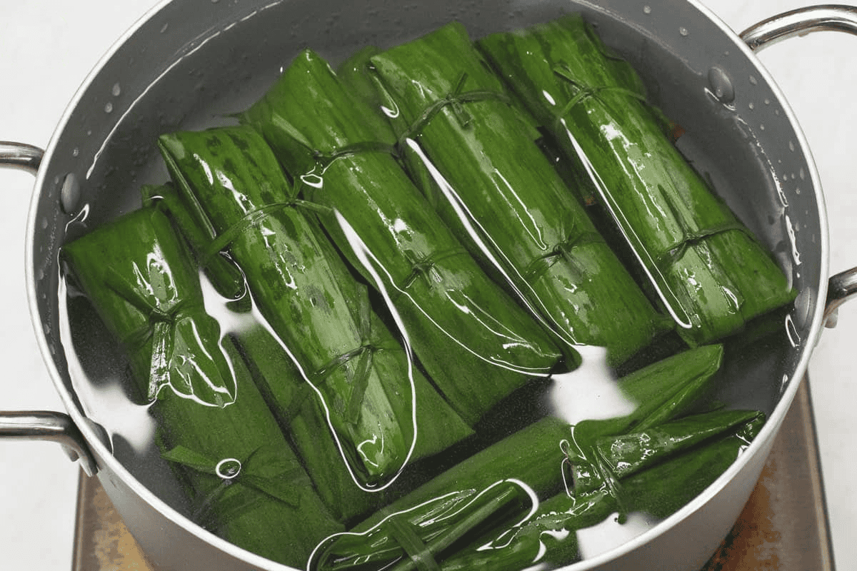 Submerging the wrapped suman in water in the pot.