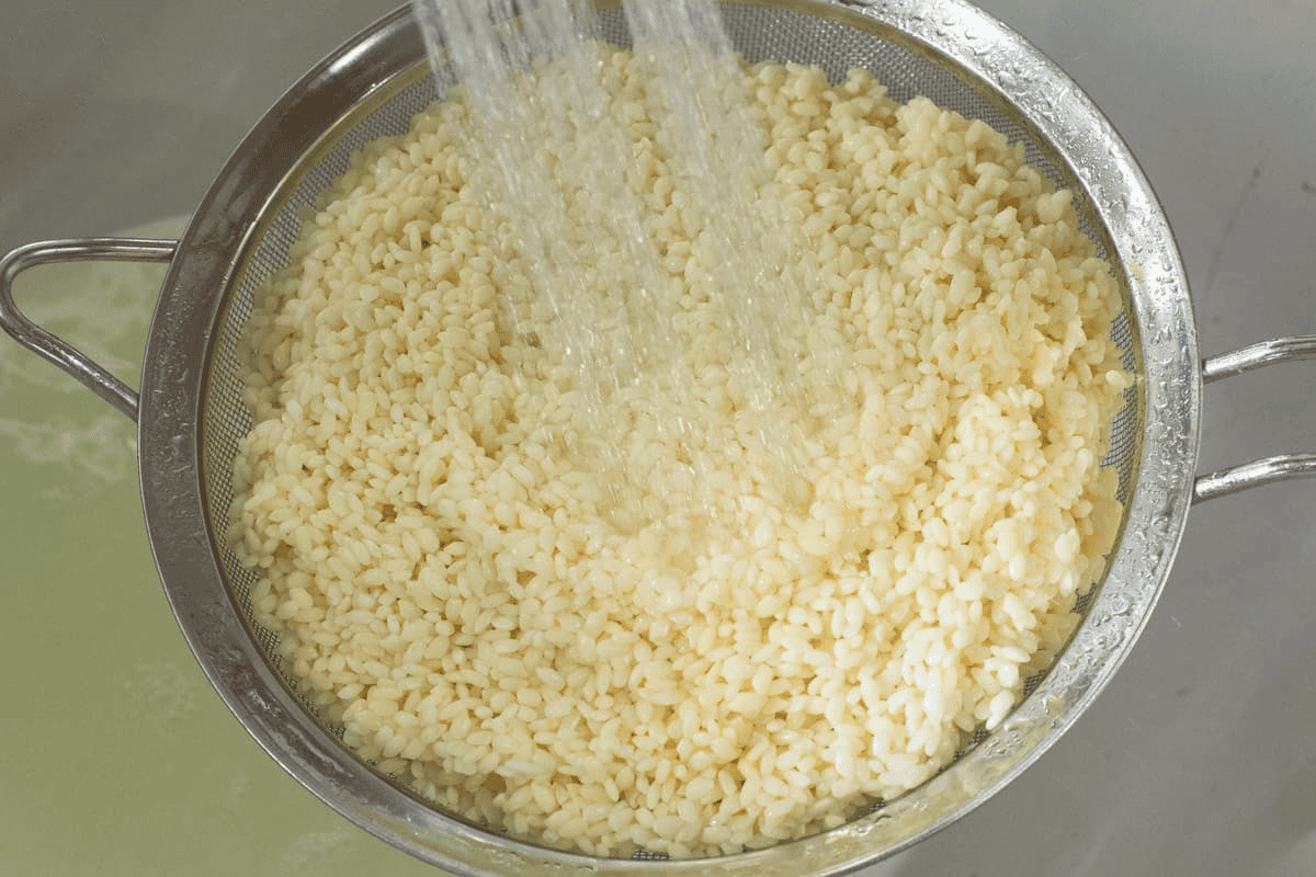 Rinsing the soaked rice under tap water.