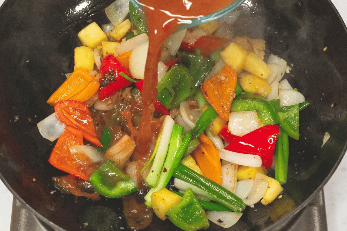 Adding the sweet and sour sauce to the wok.