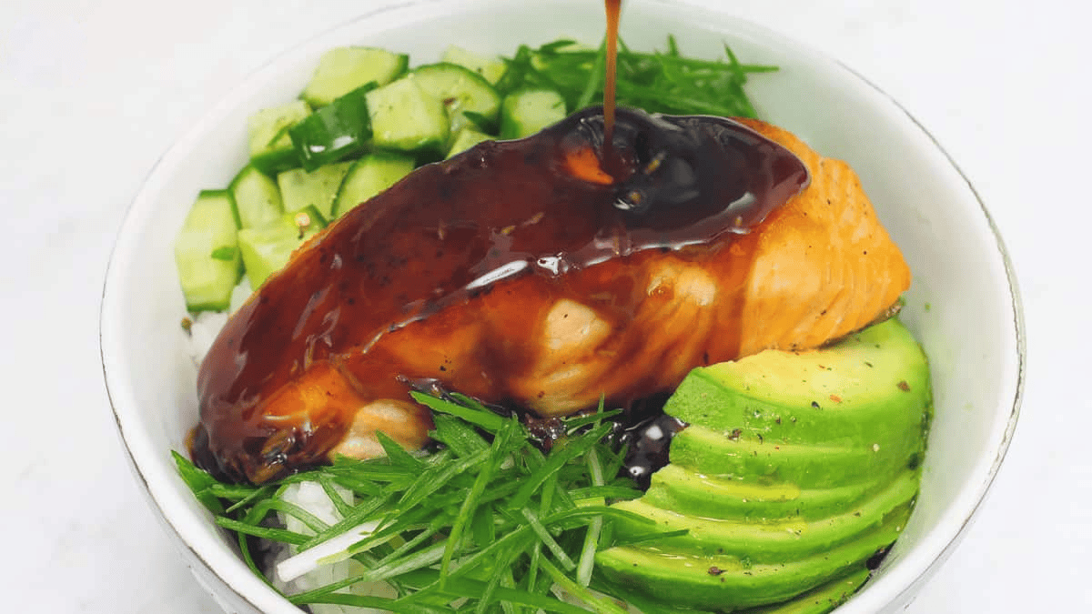 Pouring the teriyaki sauce over the bowl of salmon, rice, and vegetables.