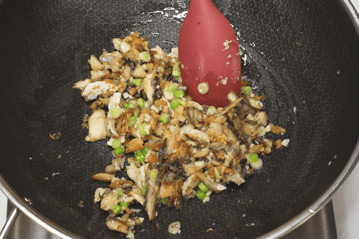 Sauteing the aromatics with the tinapa flakes in a wok.