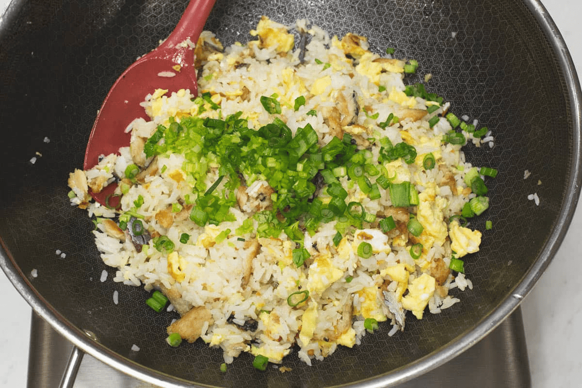 Tinapa Fried Rice with scallions in a wok.