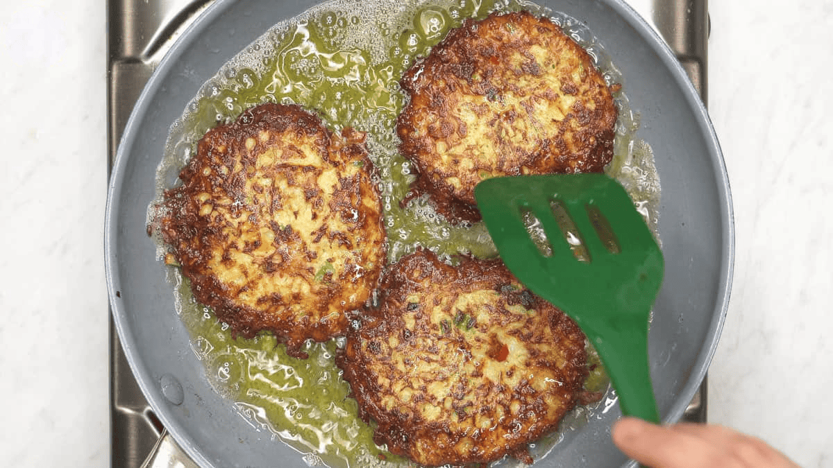 Frying the chayote patties in a skillet until nicely browned.