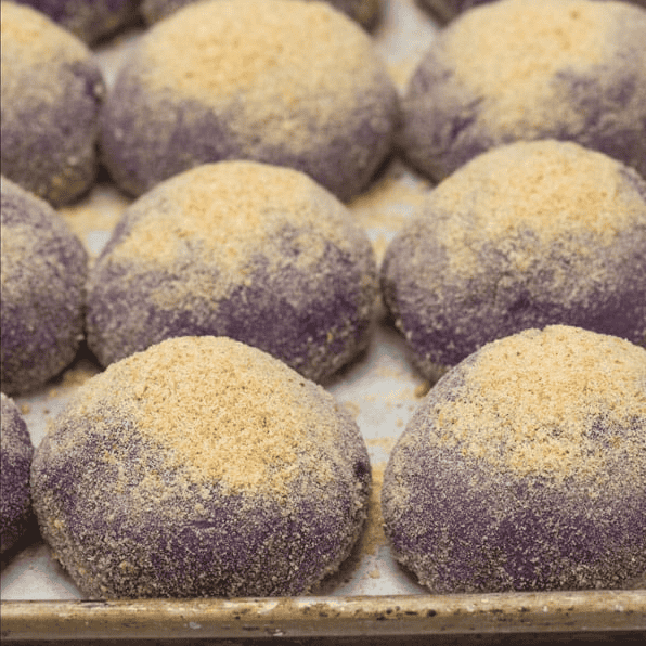 Baked ube pandesal on a baking sheet.